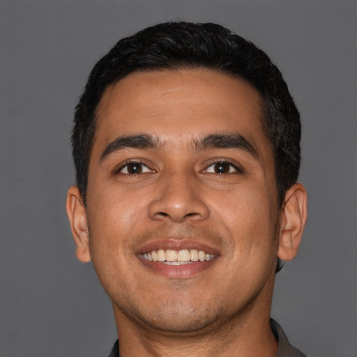 Joyful latino young-adult male with short  black hair and brown eyes