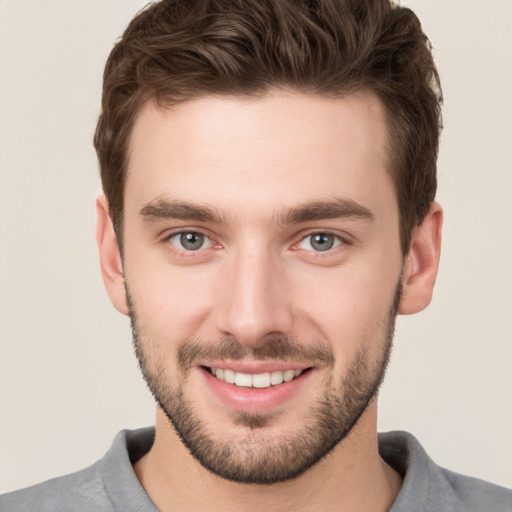 Joyful white young-adult male with short  brown hair and grey eyes