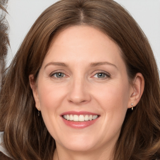 Joyful white adult female with long  brown hair and grey eyes