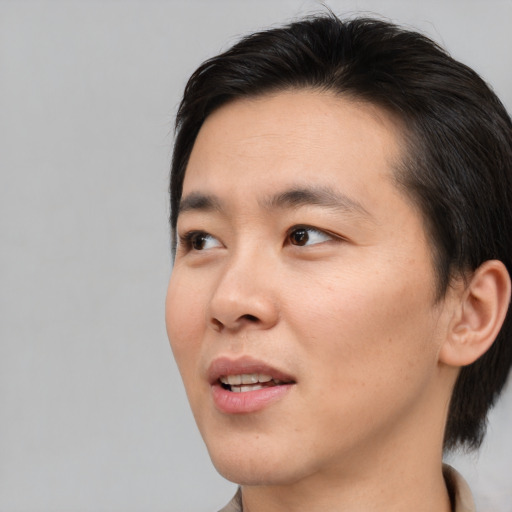 Joyful asian young-adult male with short  brown hair and brown eyes