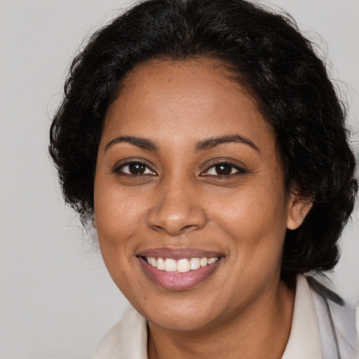 Joyful black young-adult female with long  brown hair and brown eyes