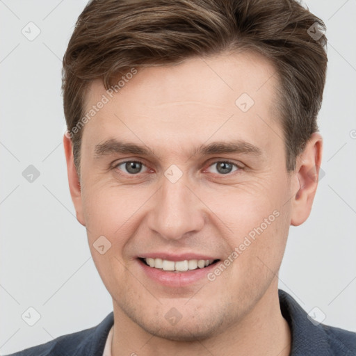 Joyful white young-adult male with short  brown hair and grey eyes