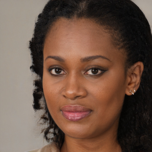 Joyful black young-adult female with long  brown hair and brown eyes