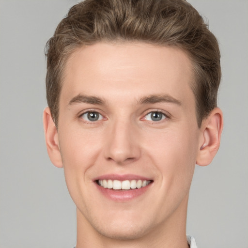 Joyful white young-adult male with short  brown hair and grey eyes