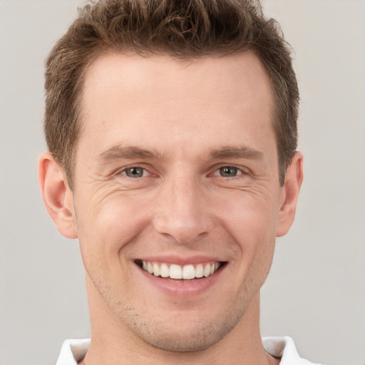 Joyful white young-adult male with short  brown hair and grey eyes