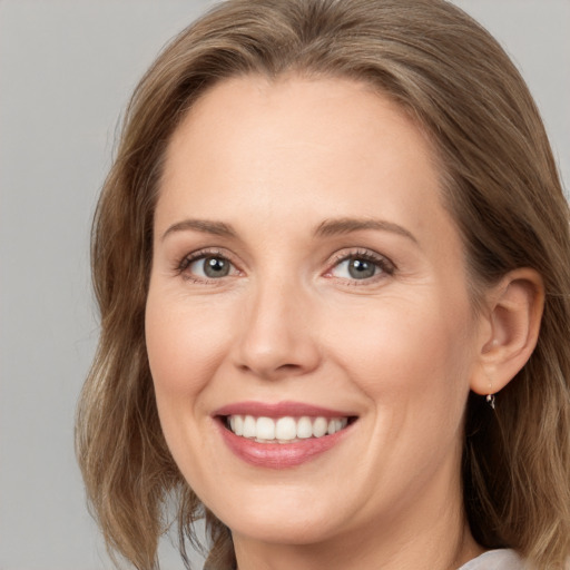 Joyful white adult female with medium  brown hair and grey eyes