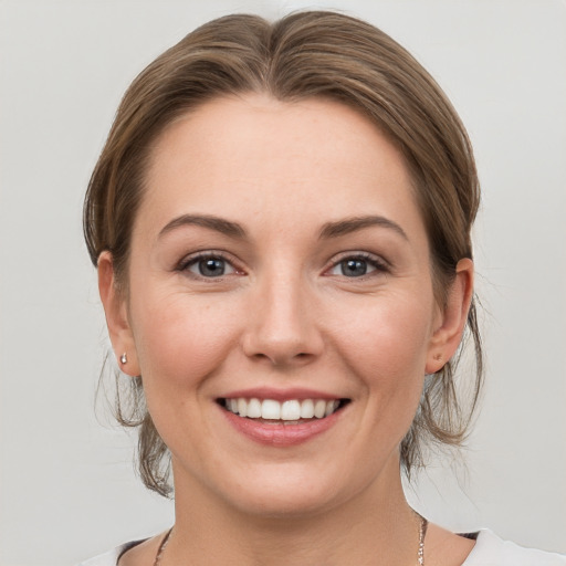 Joyful white young-adult female with medium  brown hair and grey eyes