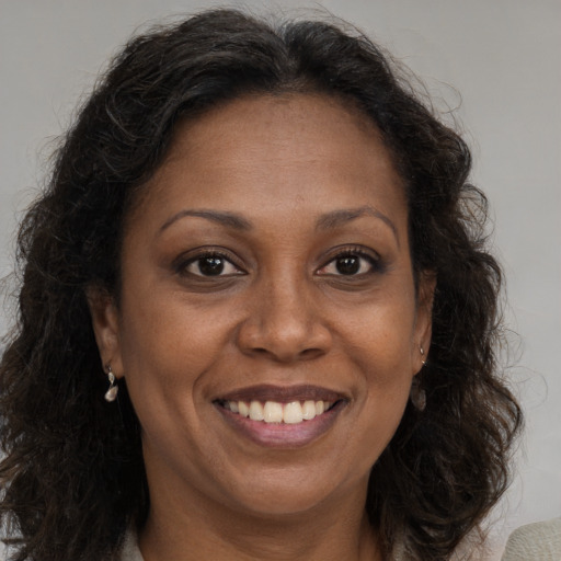 Joyful black adult female with long  brown hair and brown eyes