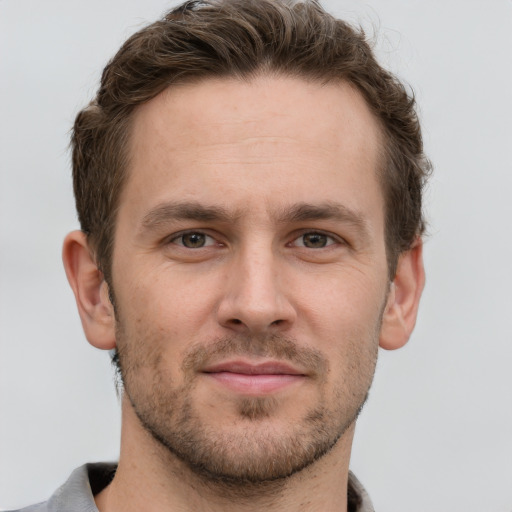 Joyful white young-adult male with short  brown hair and grey eyes