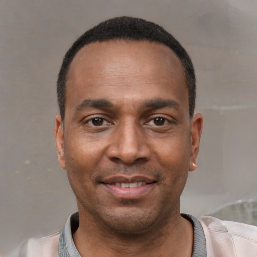 Joyful black adult male with short  black hair and brown eyes