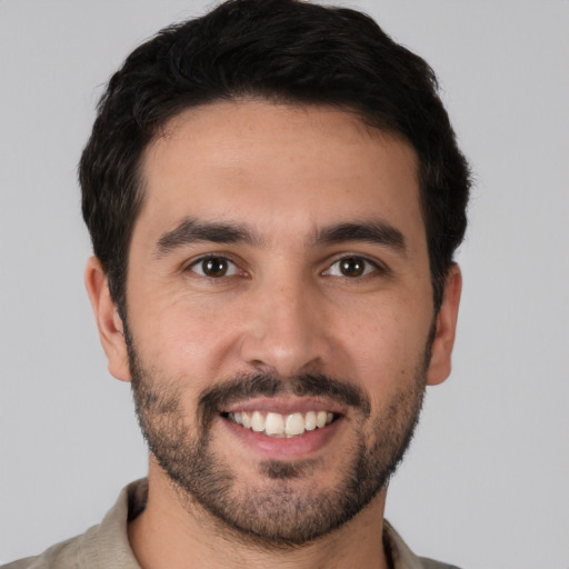 Joyful white young-adult male with short  black hair and brown eyes