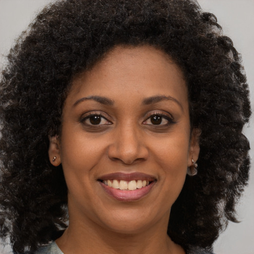 Joyful black young-adult female with long  brown hair and brown eyes