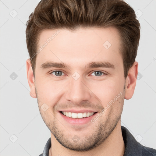 Joyful white young-adult male with short  brown hair and grey eyes