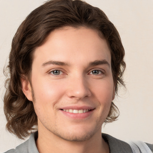 Joyful white young-adult male with medium  brown hair and grey eyes