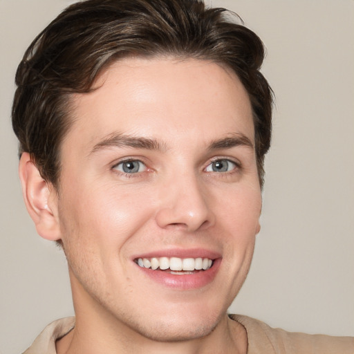 Joyful white young-adult male with short  brown hair and grey eyes