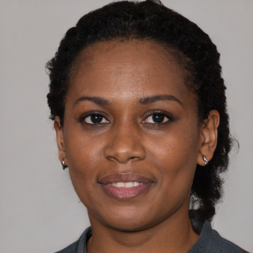 Joyful black young-adult female with short  black hair and brown eyes