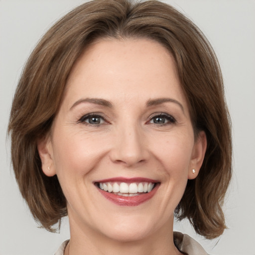 Joyful white adult female with medium  brown hair and grey eyes