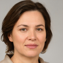 Joyful white adult female with medium  brown hair and green eyes