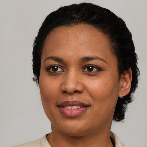 Joyful black young-adult female with short  black hair and brown eyes