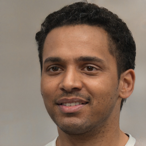 Joyful black young-adult male with short  black hair and brown eyes