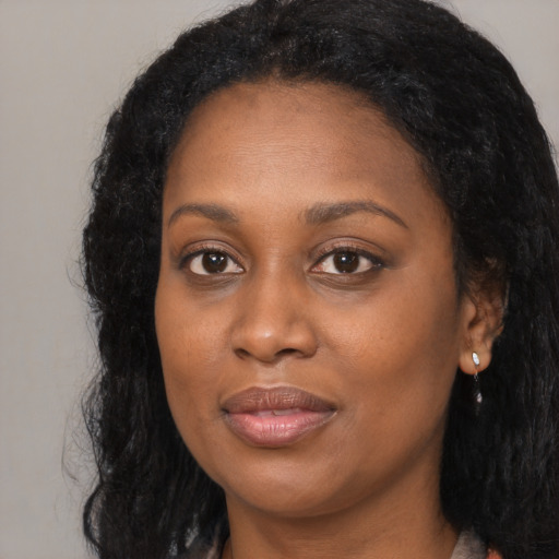 Joyful black young-adult female with long  black hair and brown eyes