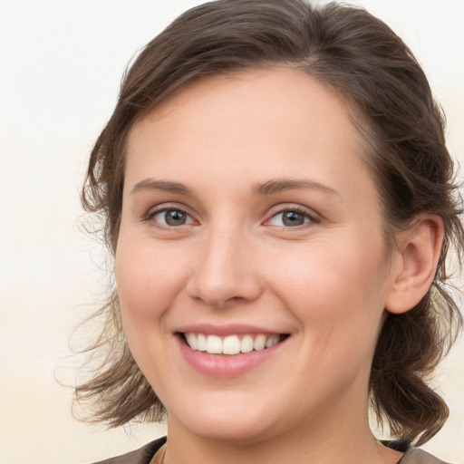 Joyful white young-adult female with medium  brown hair and grey eyes