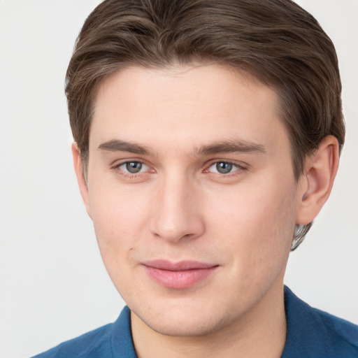 Joyful white young-adult male with short  brown hair and grey eyes