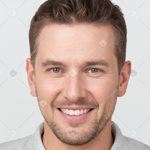 Joyful white young-adult male with short  brown hair and grey eyes