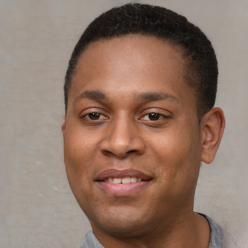 Joyful black young-adult male with short  brown hair and brown eyes