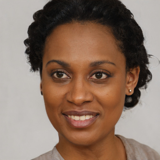 Joyful black young-adult female with short  black hair and brown eyes