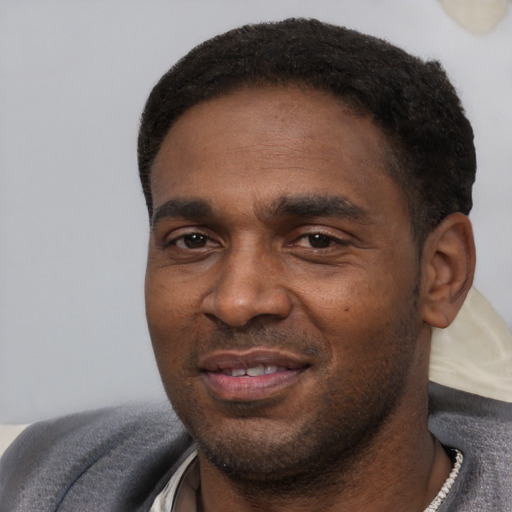 Joyful black young-adult male with short  black hair and brown eyes