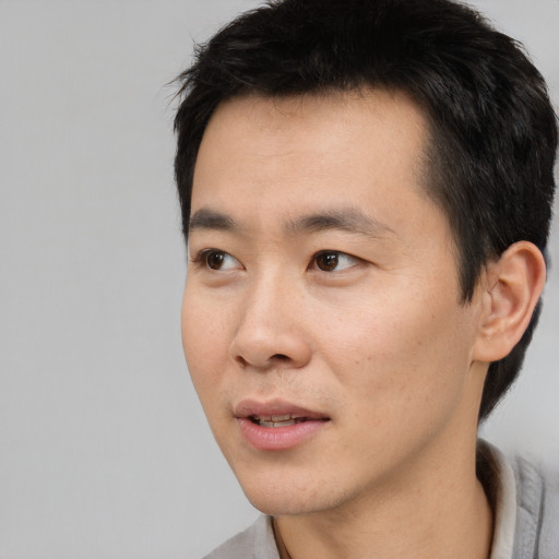 Joyful asian young-adult male with short  black hair and brown eyes