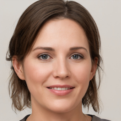 Joyful white young-adult female with medium  brown hair and grey eyes