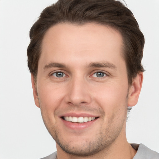 Joyful white young-adult male with short  brown hair and grey eyes