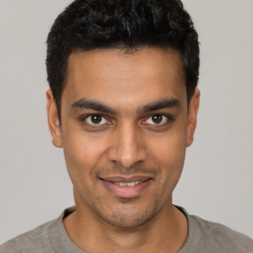 Joyful latino young-adult male with short  black hair and brown eyes