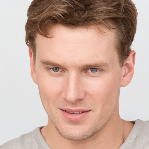 Joyful white young-adult male with short  brown hair and blue eyes