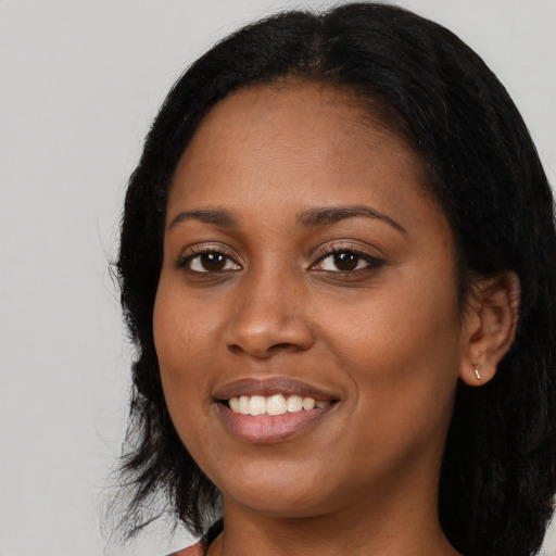 Joyful black young-adult female with long  black hair and brown eyes