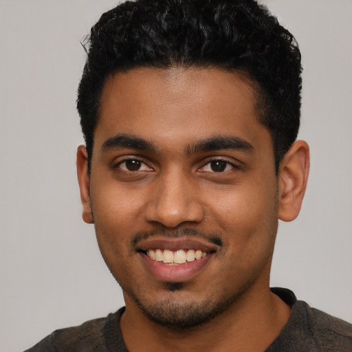 Joyful black young-adult male with short  black hair and brown eyes