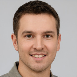 Joyful white young-adult male with short  brown hair and grey eyes