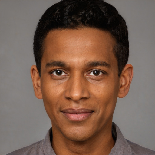 Joyful black young-adult male with short  black hair and brown eyes