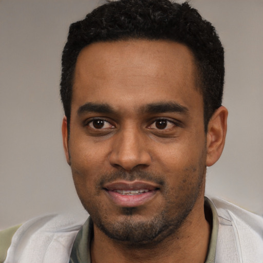Joyful black young-adult male with short  black hair and brown eyes