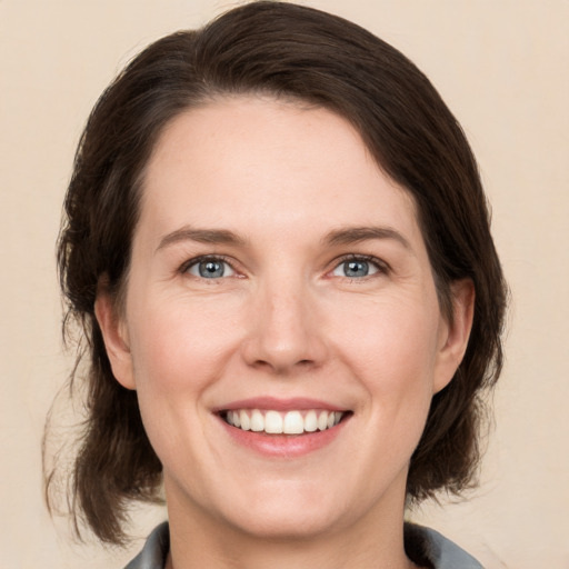 Joyful white adult female with medium  brown hair and grey eyes