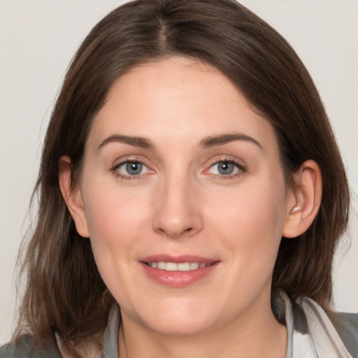 Joyful white young-adult female with medium  brown hair and grey eyes