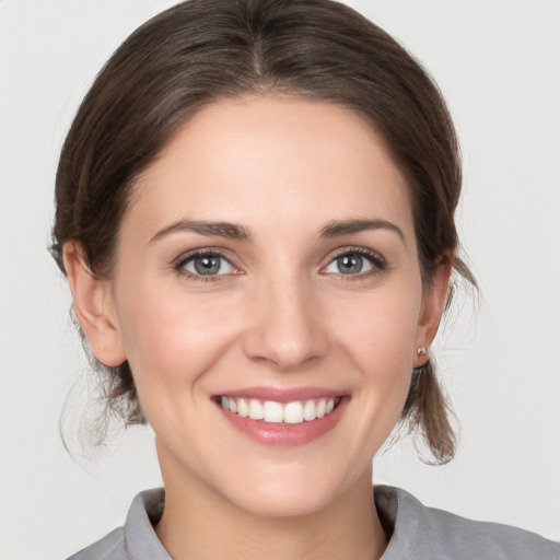 Joyful white young-adult female with medium  brown hair and grey eyes