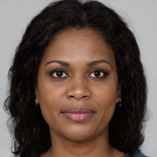 Joyful black young-adult female with long  brown hair and brown eyes