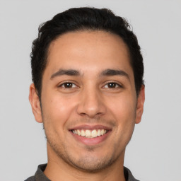 Joyful latino young-adult male with short  brown hair and brown eyes