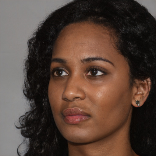 Joyful black young-adult female with long  black hair and brown eyes