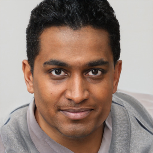 Joyful black young-adult male with short  brown hair and brown eyes