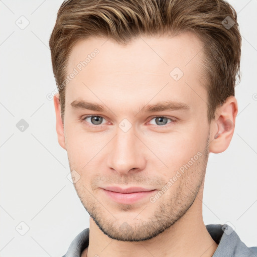 Joyful white young-adult male with short  brown hair and grey eyes