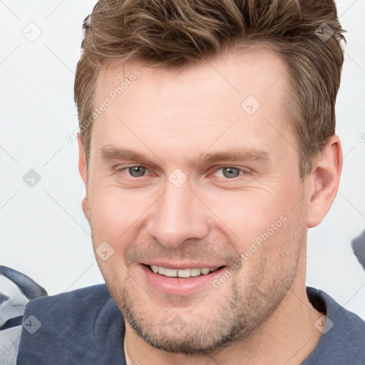 Joyful white young-adult male with short  brown hair and grey eyes